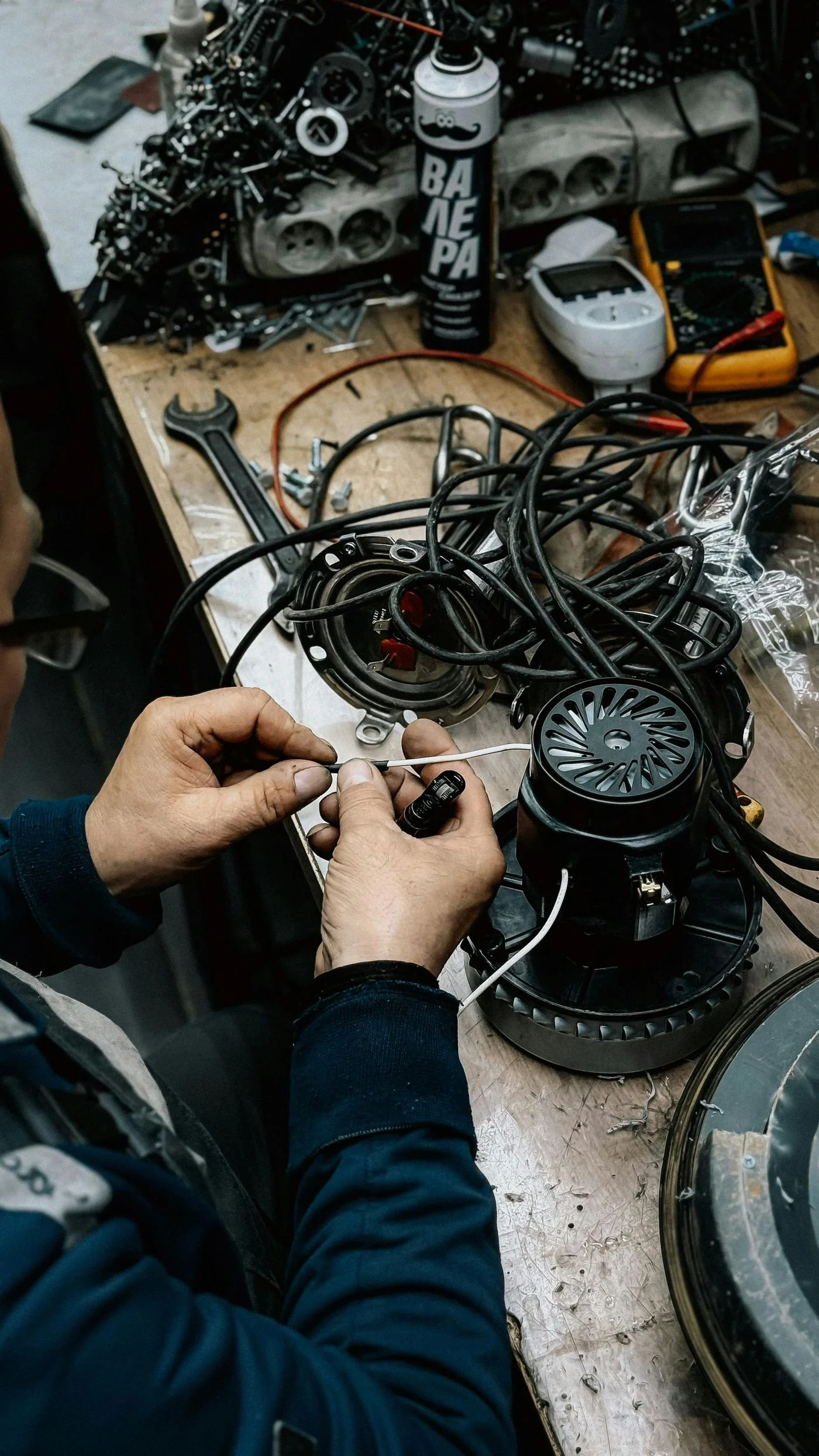 Technician performing electrical diagnostics on HVAC motor assembly with multimeter and wiring harness