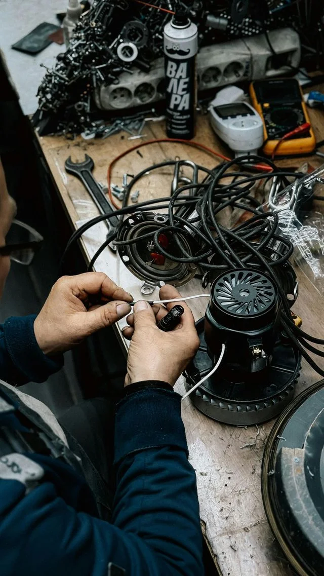 Technician repairing HVAC motor wiring and electrical components with diagnostic tools